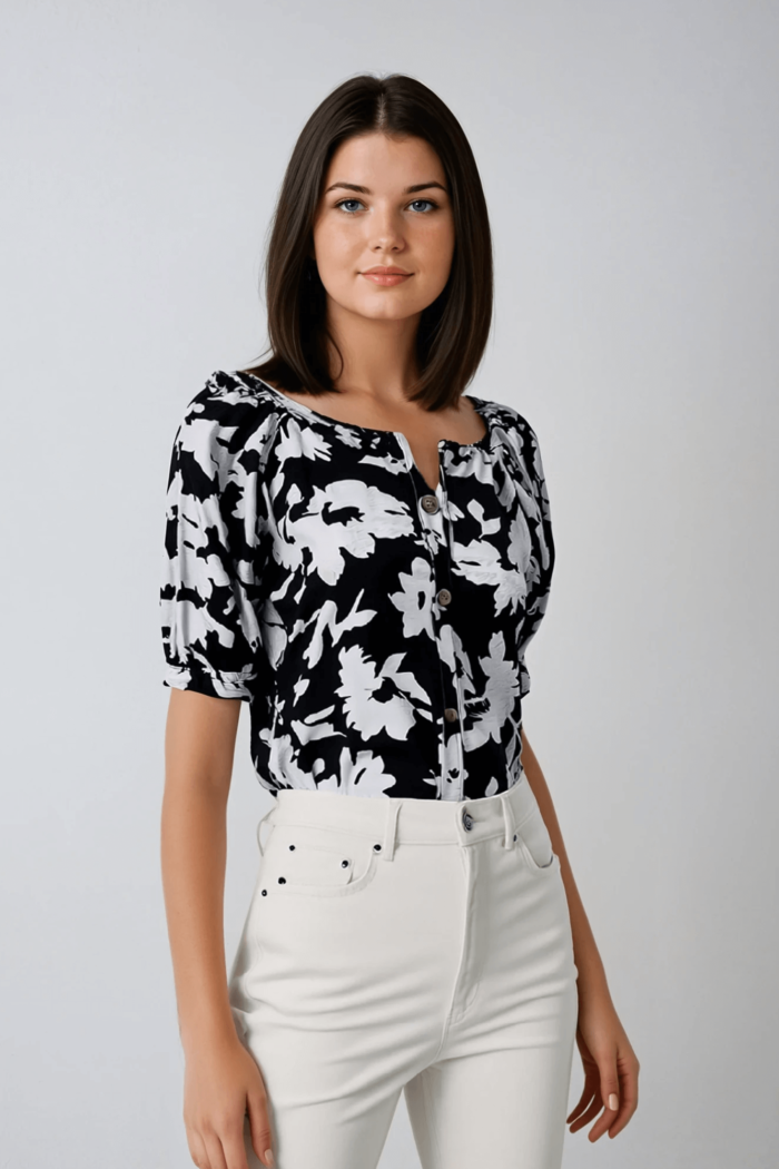 Blusa blanca y negra con estampado floral, cuello redondo y mangas abullonadas.